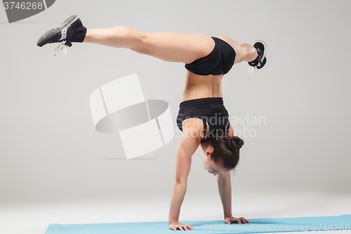 Image of Beautiful sporty girl standing in acrobat pose or yoga asana