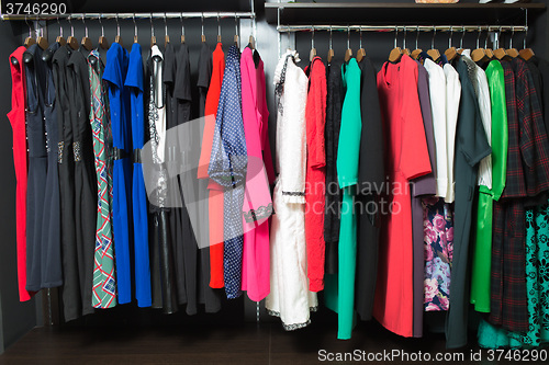 Image of women\'s dresses on hangers in a retail shop