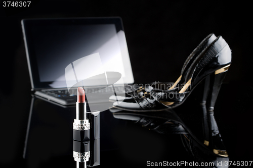 Image of laptop, lipstick and shoes. black background. female set. Online buying cosmetics