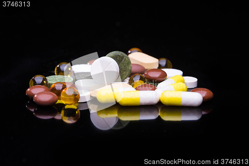 Image of Pile of various colorful pills isolated on black