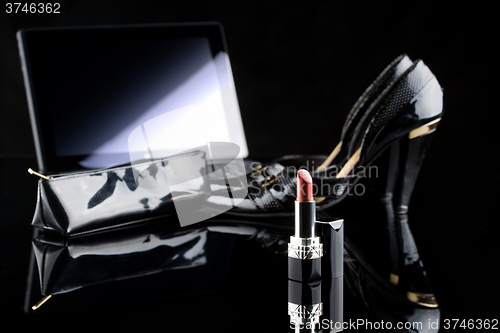 Image of laptop, lipstick and shoes. black background. female set. Online buying cosmetics