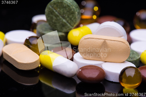 Image of Pile of various colorful pills isolated on black