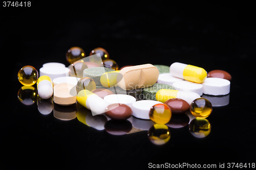 Image of Pile of various colorful pills isolated on black