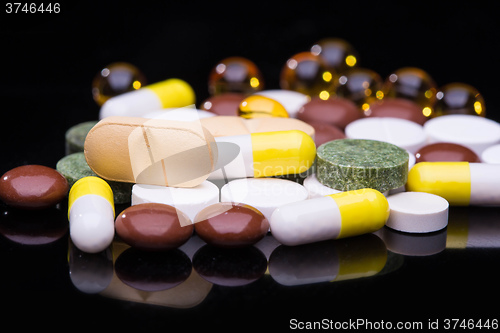 Image of Pile of various colorful pills isolated on black