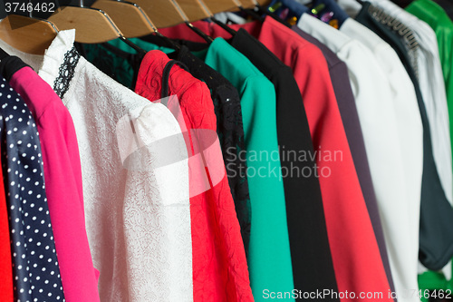 Image of women\'s dresses on hangers in a retail shop