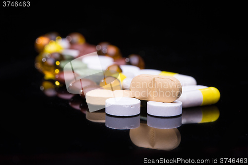 Image of Pile of various colorful pills isolated on black