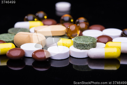 Image of Pile of various colorful pills isolated on black