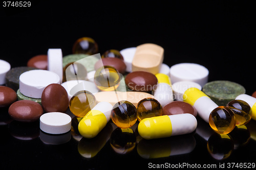 Image of Pile of various colorful pills isolated on black