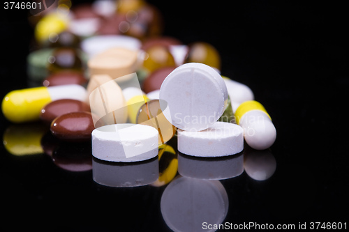 Image of Pile of various colorful pills isolated on black