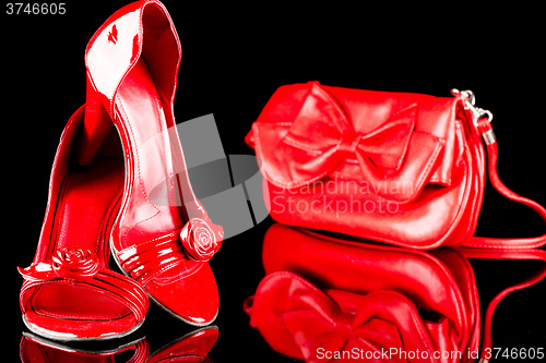 Image of luxury red high heel women shoes and a bag on black background. reflection