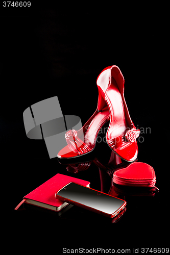 Image of red phone, women\'s high-heeled shoes and a notebook. set. black background. 