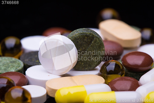 Image of Pile of various colorful pills isolated on black