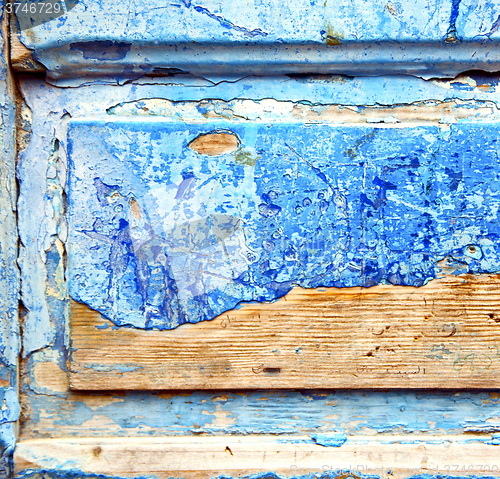 Image of dirty stripped paint in the blue wood door and rusty nail