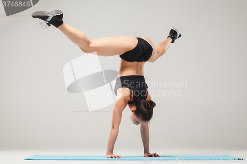 Image of Beautiful sporty girl standing in acrobat pose or yoga asana