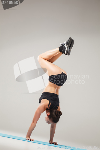 Image of Beautiful sporty girl standing in acrobat pose or yoga asana