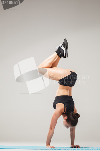 Image of Beautiful sporty girl standing in acrobat pose or yoga asana