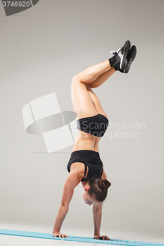 Image of Beautiful sporty girl standing in acrobat pose or yoga asana