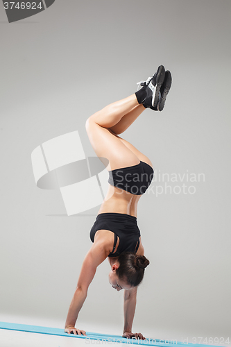 Image of Beautiful sporty girl standing in acrobat pose or yoga asana