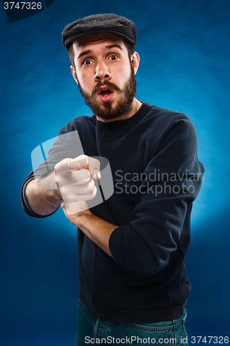 Image of Young man in cap, finger pointing towards the camera 