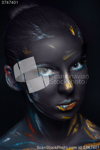 Image of Portrait of a young woman who is posing covered with  black paint 