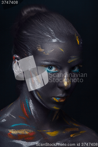 Image of Portrait of a young woman who is posing covered with  black paint 