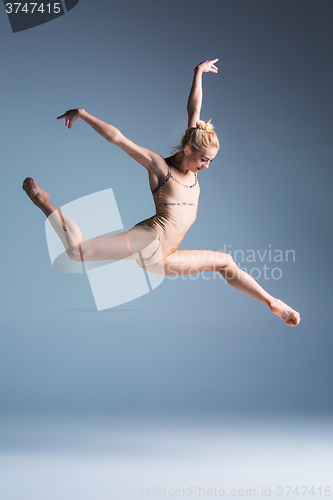 Image of Young beautiful modern style dancer jumping on a studio background