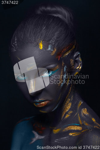 Image of Portrait of a young woman who is posing covered with  black paint 