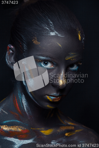 Image of Portrait of a young woman who is posing covered with  black paint 