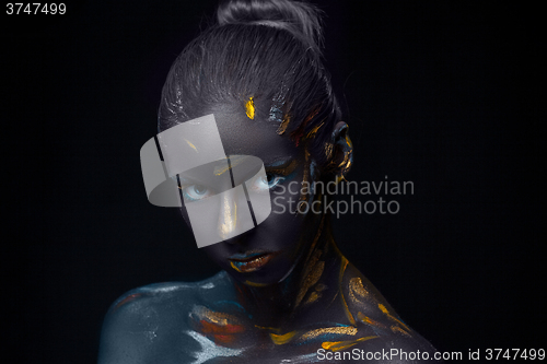 Image of Portrait of a young woman who is posing covered with  black paint 