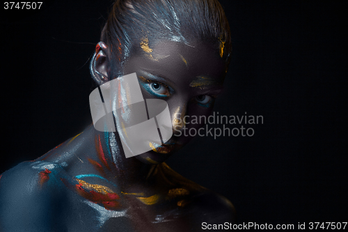 Image of Portrait of a young woman who is posing covered with  black paint 