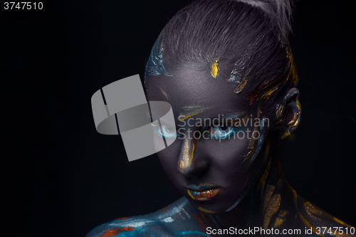 Image of Portrait of a young woman who is posing covered with  black paint 