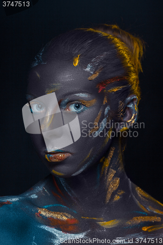 Image of Portrait of a young woman who is posing covered with  black paint 