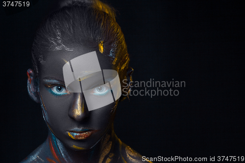 Image of Portrait of a young woman who is posing covered with  black paint 