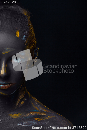 Image of Portrait of a young woman who is posing covered with  black paint 