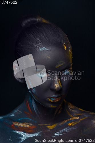 Image of Portrait of a young woman who is posing covered with  black paint 