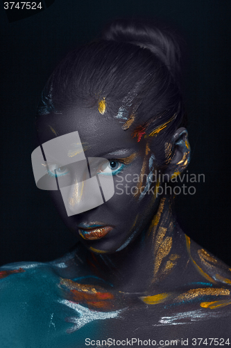 Image of Portrait of a young woman who is posing covered with  black paint 