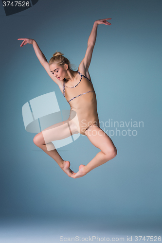 Image of Young beautiful modern style dancer jumping on a studio background