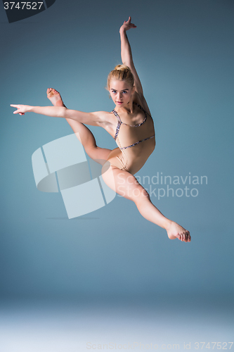 Image of Young beautiful modern style dancer jumping on a studio background