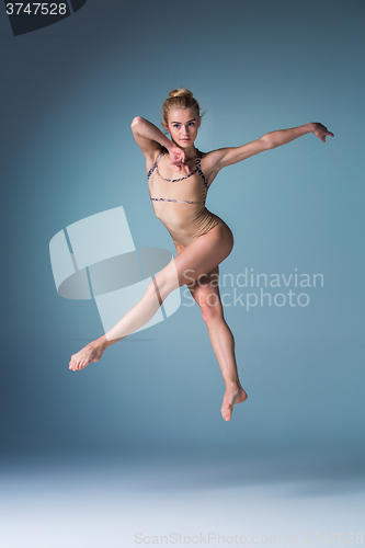 Image of Young beautiful modern style dancer jumping on a studio background