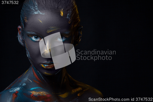 Image of Portrait of a young woman who is posing covered with  black paint 