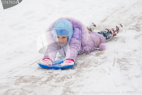 Image of Girl is rolling on his stomach with a headfirst slide snow