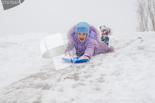 Image of Girl rolls down on his stomach with a headfirst slide snow