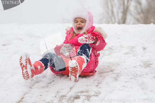 Image of A girl screaming and shrieking ice slides down hill