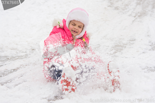 Image of Girl rolls down a hill of snow closed her eyes came off the boots