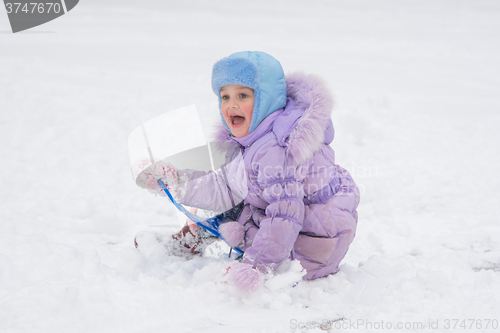 Image of Happy little girl slid down the icy hill and happily watching the other children