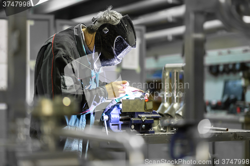 Image of Industrial worker welding in metal factory.