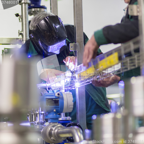 Image of Industrial worker welding in metal factory.