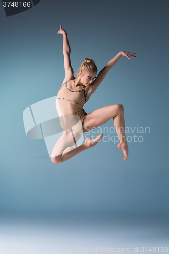 Image of Young beautiful modern style dancer jumping on a studio background