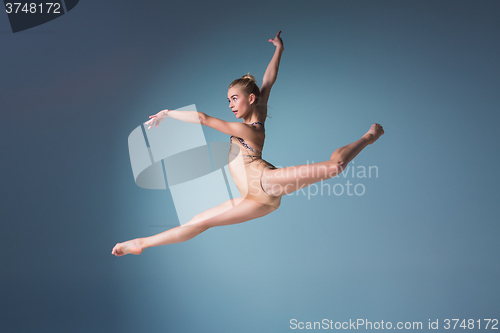 Image of Young beautiful modern style dancer jumping on a studio background