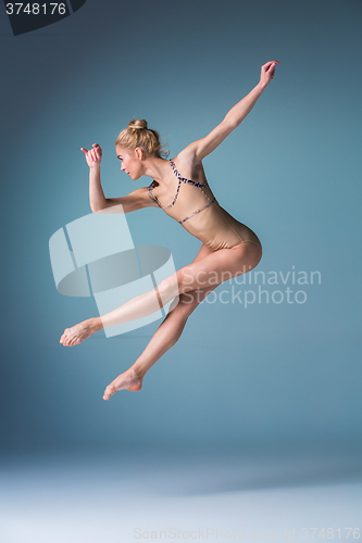 Image of Young beautiful modern style dancer jumping on a studio background